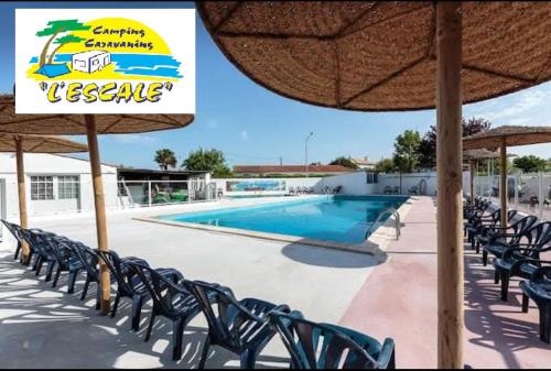 - une piscine avec des chaises et un panneau à côté dans l'établissement mobil Home à Meschers au camping l'Escale proche de Royan, à Meschers-sur-Gironde