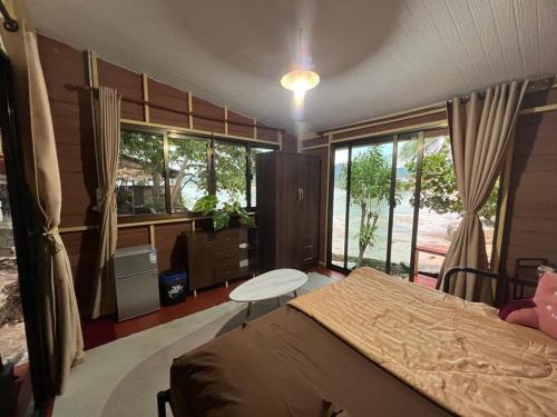 a bedroom with a bed and a table and windows at Smiley Bungalows Guesthouse in Srithanu