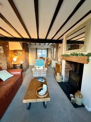 a living room with a couch and a fireplace at Fitzherbert Cottage in Swynnerton