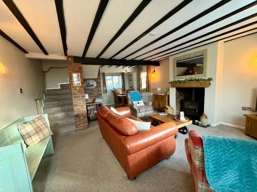 a living room with a couch and a fireplace at Fitzherbert Cottage in Swynnerton