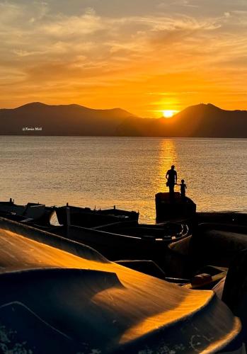 a man standing on a dock at sunset with boats at Sea Living Sicilia Apartment in Santa Flavia