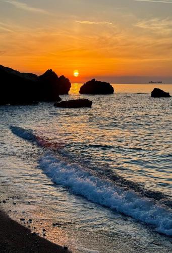 a sunset on the beach with rocks in the water at Sea Living Sicilia Apartment in Santa Flavia