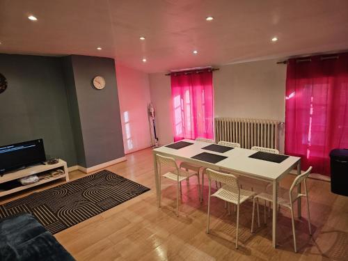 - un salon avec une table et des rideaux roses dans l'établissement Le Léon Cladel T3 proche parking gratuit, à Montauban
