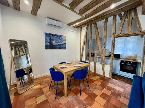 ein Esszimmer mit einem Holztisch und blauen Stühlen in der Unterkunft Le Bleuet de Rouen in Rouen