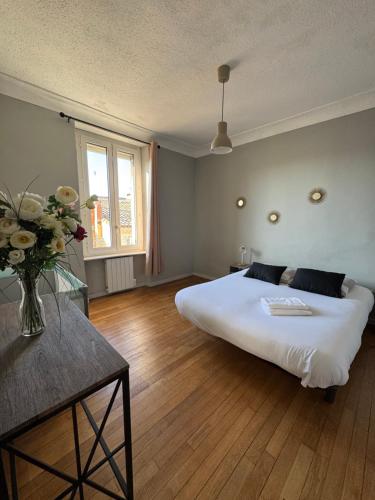 - une chambre avec un lit blanc et un vase de fleurs dans l'établissement Centre ville - Proche cité médiévale, à Carcassonne