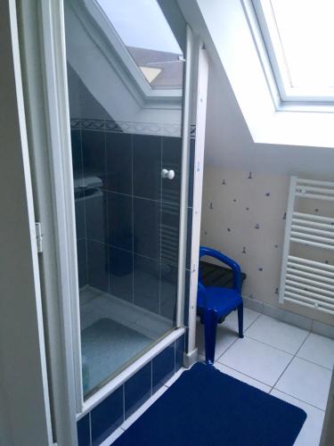 La salle de bains est pourvue d'une douche en verre avec un tabouret bleu. dans l'établissement Relax à Carnac, à Carnac