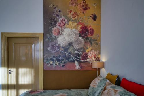 a painting of flowers on a wall next to a bed at Bed & Breakfast Bloemen Vertellen in Elst