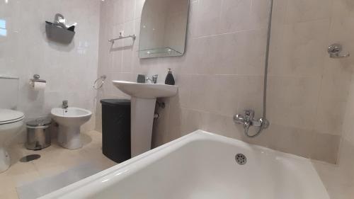 a bathroom with a tub and a sink and a toilet at Casa das Lagoas com piscina aquecida exclusiva in Bragança