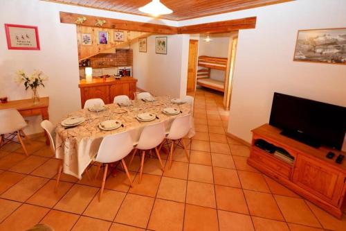 une salle à manger avec une table avec des chaises et une télévision dans l'établissement Le Chalet des Séraphins, à Saint-Sorlin-dʼArves