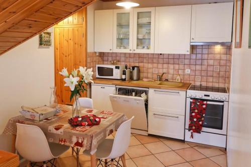 - une cuisine avec une table et des appareils électroménagers blancs dans l'établissement Le Chalet des Séraphins, à Saint-Sorlin-dʼArves