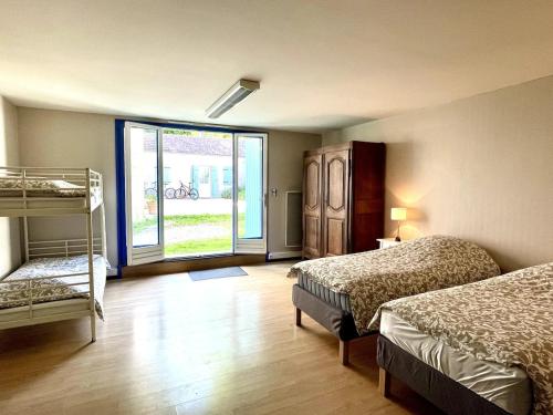 une chambre avec deux lits et une grande fenêtre dans l'établissement Charmante maison avec jardin et jacuzzi, à Voulaines