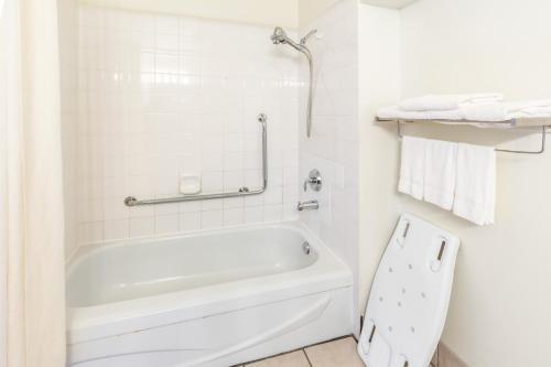 a white bathroom with a tub and a toilet at Howard Johnson by Wyndham Fort St. John in Fort Saint John