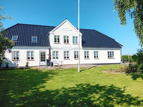 a large white house with a black roof at Elmegaard in Sønderby
