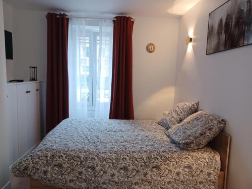 een slaapkamer met een bed en een raam met rode gordijnen bij La Demeure du Chevalier in Saint-Cyr-lʼÉcole