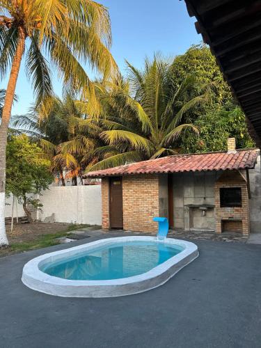 a swimming pool in front of a house with palm trees at Oásis de Férias. in Lucena
