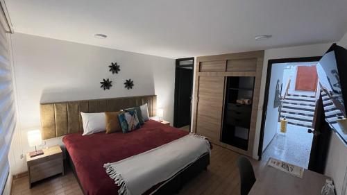 a bedroom with a large bed with a red blanket at HOSTAL SEP7IMO ARTE in Bogotá
