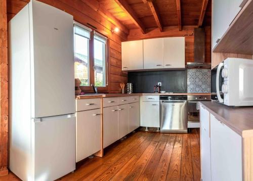 a kitchen with white appliances and a wooden ceiling at Magnifique chalet au calme total in Réau
