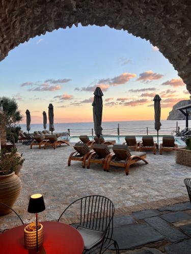 a view of the beach from an arch with chairs and tables at Kyrimai Hotel in Gerolimenas
