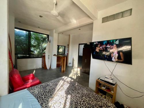 ein Schlafzimmer mit einem Bett und einem Fernseher an der Wand in der Unterkunft La Punta SurfHouse AC Starlink in Brisas de Zicatela
