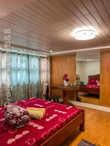 a bedroom with a large red bed and a desk at Dragon's Lair B&B in Baguio