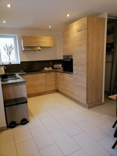 Il comprend une cuisine avec des placards en bois et du carrelage blanc. dans l'établissement Maison de village Les Marronniers, à Anse