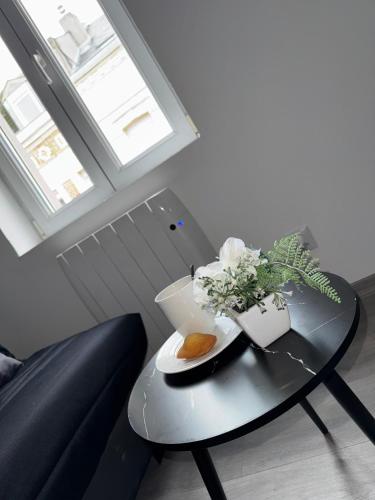 une table avec un vase de fleurs dessus dans l'établissement Agréable T2- Centre ville, à Saint-Quentin