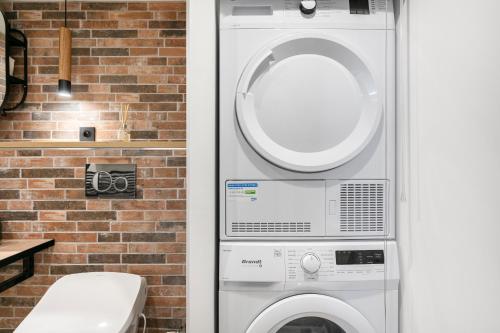 - un lave-linge et un sèche-linge à côté d'un mur en briques dans l'établissement Loft Industriel avec Terrasse et Filet Suspendu à Nice Cimiez, à Nice