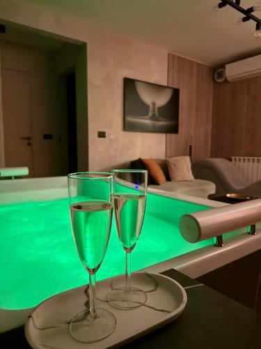 two wine glasses sitting on a table next to a pool at Jacuzzi Old Town Escape in Bucharest