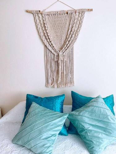 a curtain hanging on a wall above a bed with pillows at Casa Luar- suite rooms in Praia do Carvoeiro