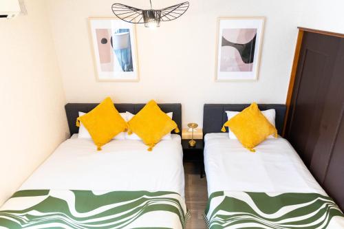 two beds in a small room with yellow pillows at BREEZE furano 205 in Furano
