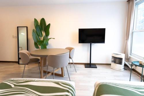 a living room with a table and a flat screen tv at BREEZE furano 205 in Furano
