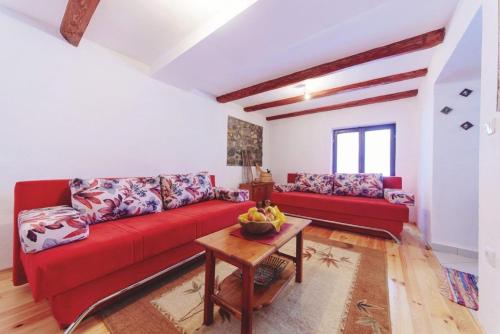 a living room with a red couch and a table at Malo selo Kurikuce in Berane