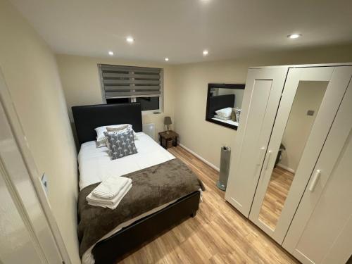 a small bedroom with a bed and a mirror at The Cosy Cottage, Old Soles bridge Lane in Chorleywood