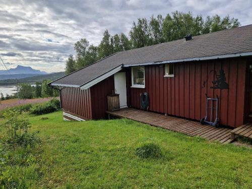 a red house with a wooden deck in the grass at Cabin with lovely view in Lakså