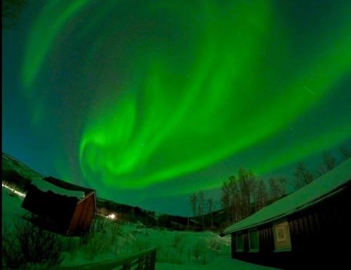 an aurora in the sky over a house and a barn at Cabin with lovely view in Lakså