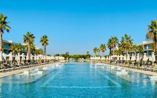 a resort swimming pool with chairs and palm trees at Dreamscape at San Pietro Premium - next to Meliá in Lalzit Bay