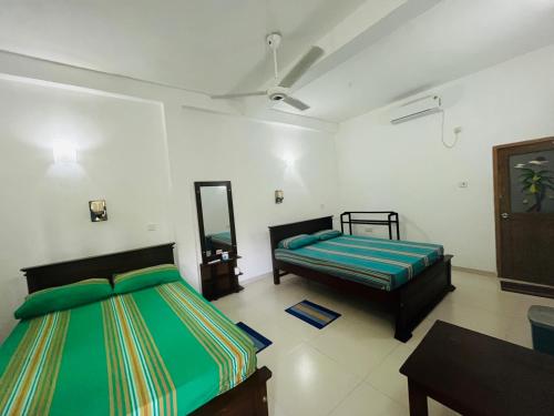 a bedroom with two beds and a mirror at Nature Trails Inn Sinharaja in Deniyaya
