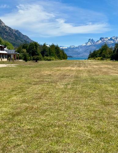 a large field of grass with mountains in the background at El Pedregoso Casa Amarilla in Cholila