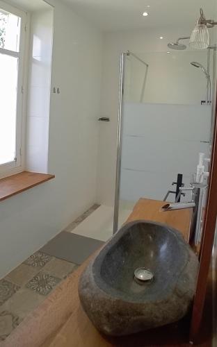 a bathroom with a stone sink and a shower at Chambres et table d'hôte Rabillou in Saint-Moreil