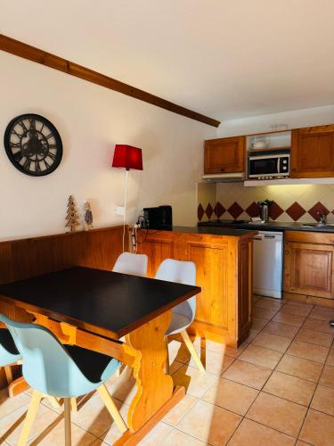 une cuisine avec une table et des chaises et une horloge au mur dans l'établissement Appartement Vu Mont Blanc parking Terrasse, à Chamonix-Mont-Blanc