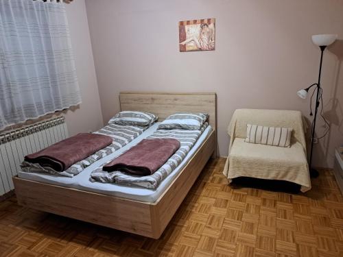 a bedroom with two beds and a chair at Studio apartment Meli in Ogulin