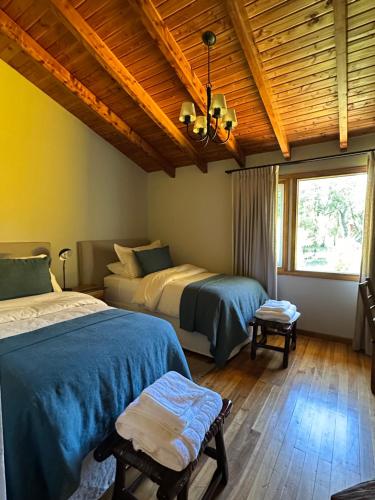 a bedroom with two beds and a wooden ceiling at El Pedregoso Casa Amarilla in Cholila