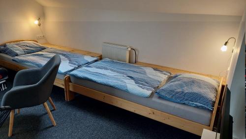 a bedroom with two twin beds and a chair at Apartmány Kousek od jezera in Doksy