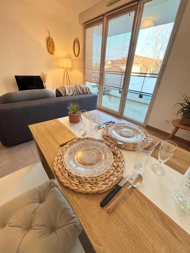 une table avec des assiettes et des verres au-dessus dans l'établissement Proche Genève - Cosy Appartement, à Reignier-Ésery