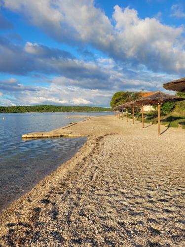 a sandy beach with umbrellas and the water at Villa Kaktusa in Pirovac