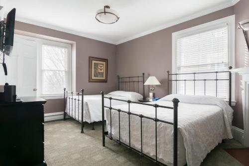 a bedroom with two beds and two windows at Longwood Inn in Brookline