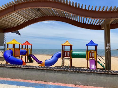 a playground on a beach with the ocean in the background at Apêzinho Aconchegante e Decorado in Anchieta