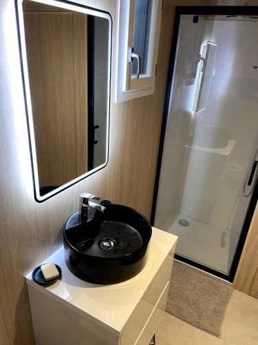 une salle de bain avec un lavabo noir et un miroir dans l'établissement Ma Cabane au fond du jardin, à Plouharnel