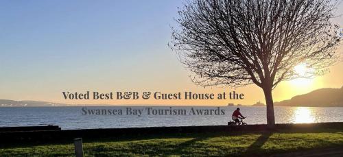a person riding a bike next to a tree at Tides Reach Guest House in The Mumbles