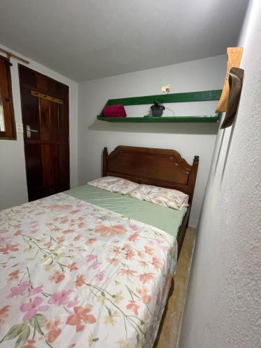 a bedroom with a bed with a floral bedspread at Suítes Cachadaço Beach in Paraty